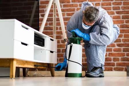 pest control technician spraying house